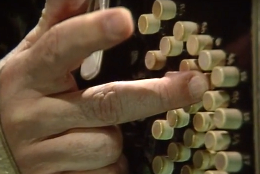 Close view of Astor Piazzolla's right hand pressing the white buttons of a bandoneón during a 1984 performance.
