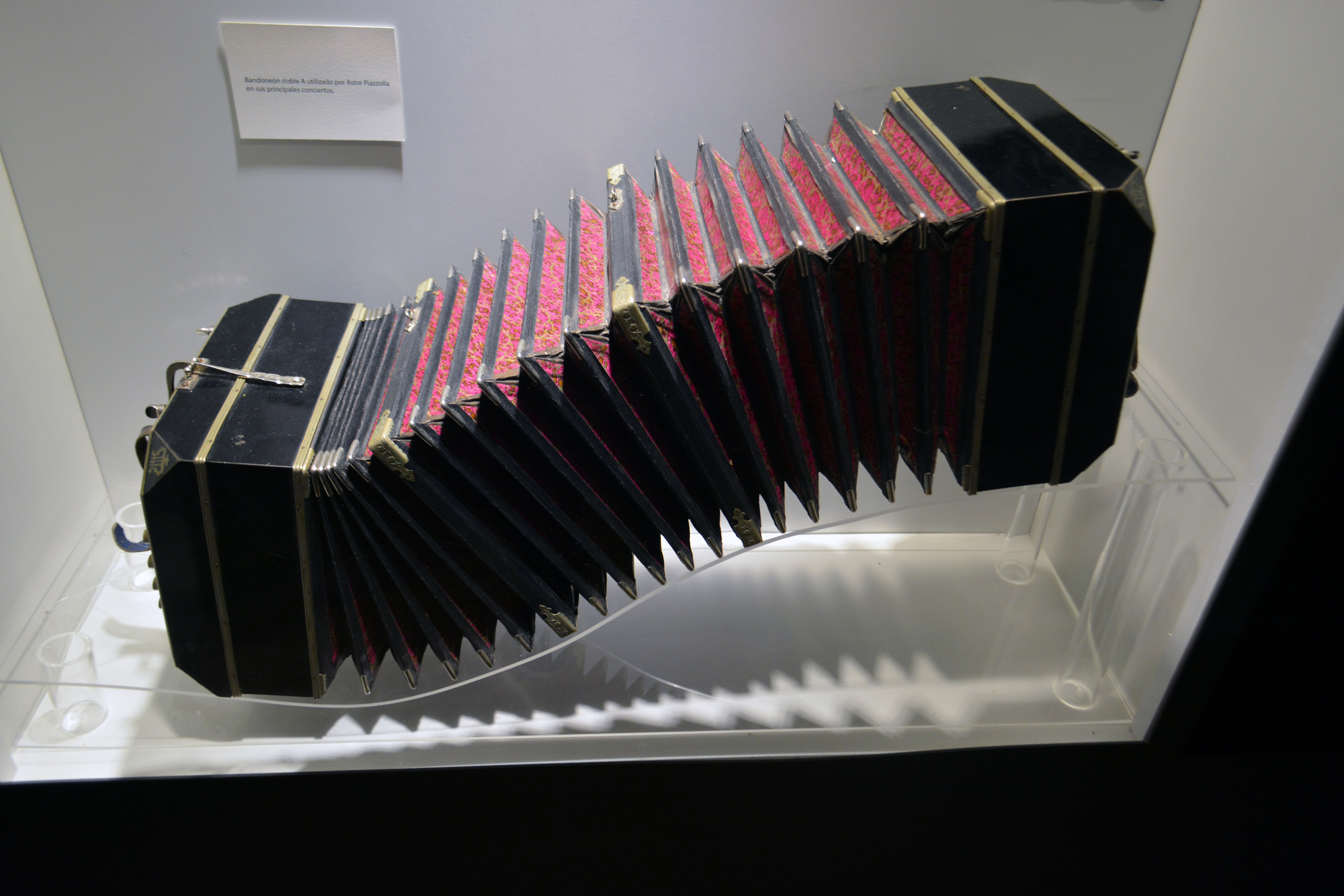 Astor Piazzolla's black double-A bandoneón displayed open in a museum case.