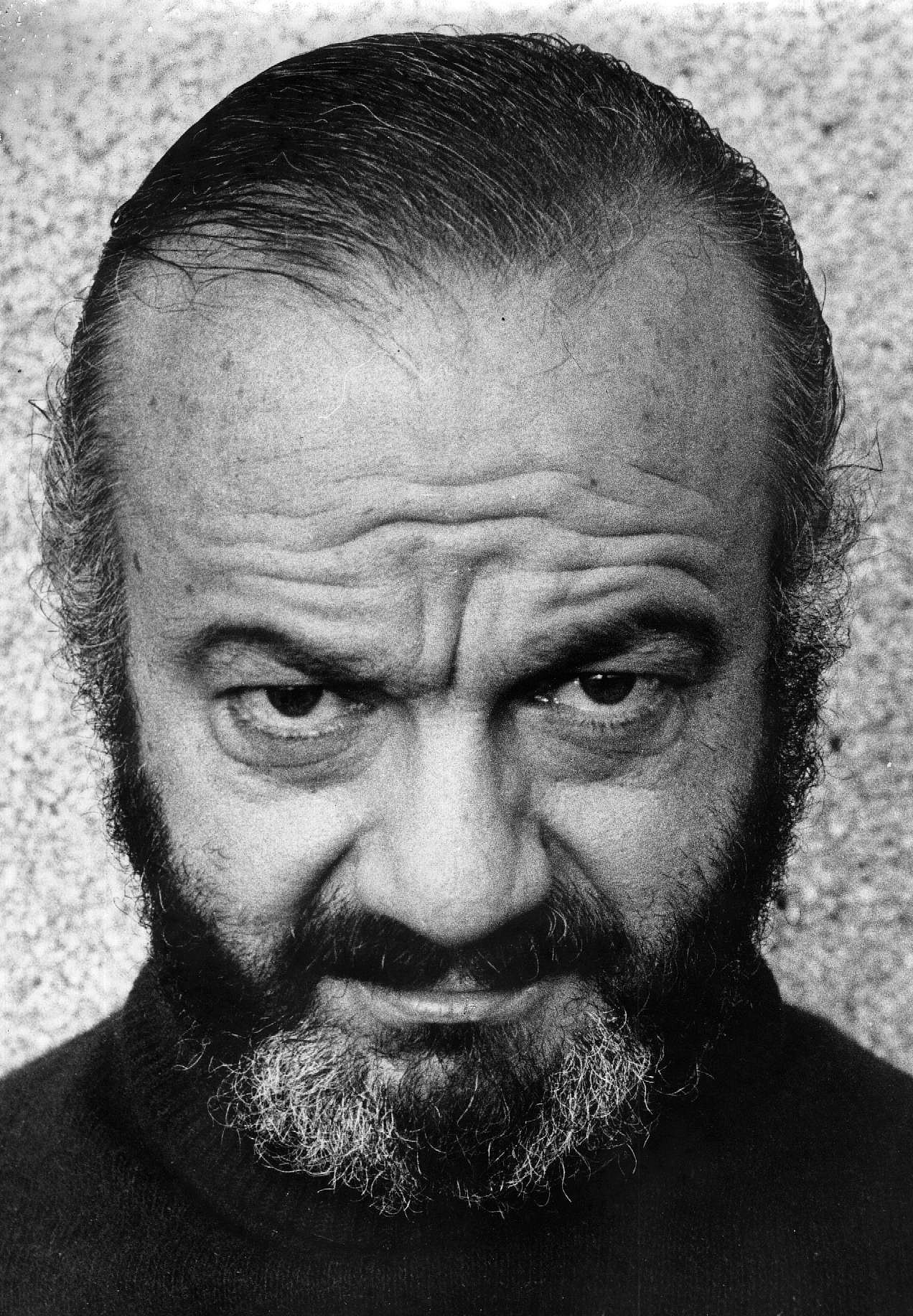 Black-and-white close portrait of Astor Piazzolla with a direct gaze and beard.