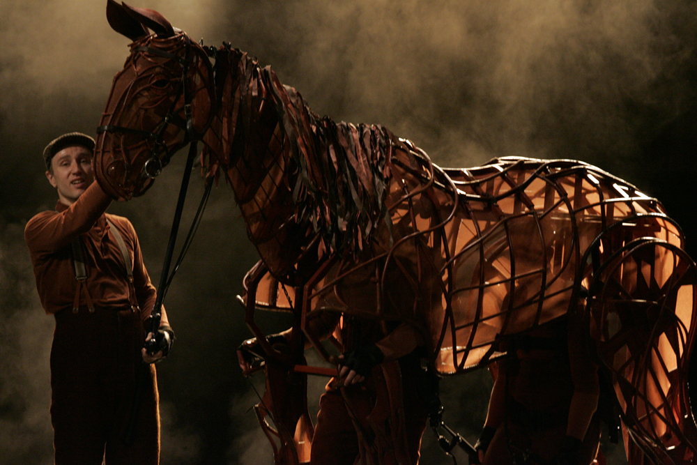 War Horse puppet operated by visible performers on a smoky stage