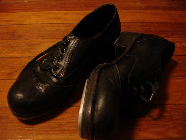 A pair of tap shoes shown sole-up, with metal taps visible at heel and toe.
