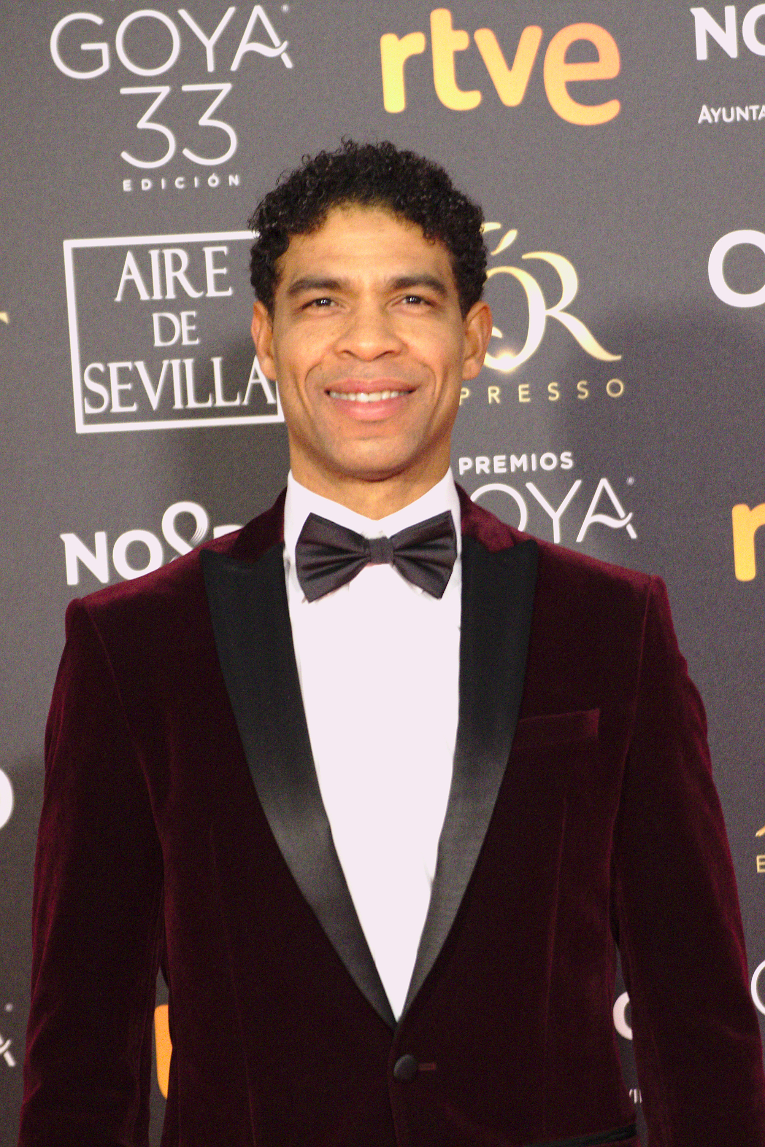 Formal portrait of Carlos Acosta in a burgundy dinner jacket at the 2019 Goya Awards