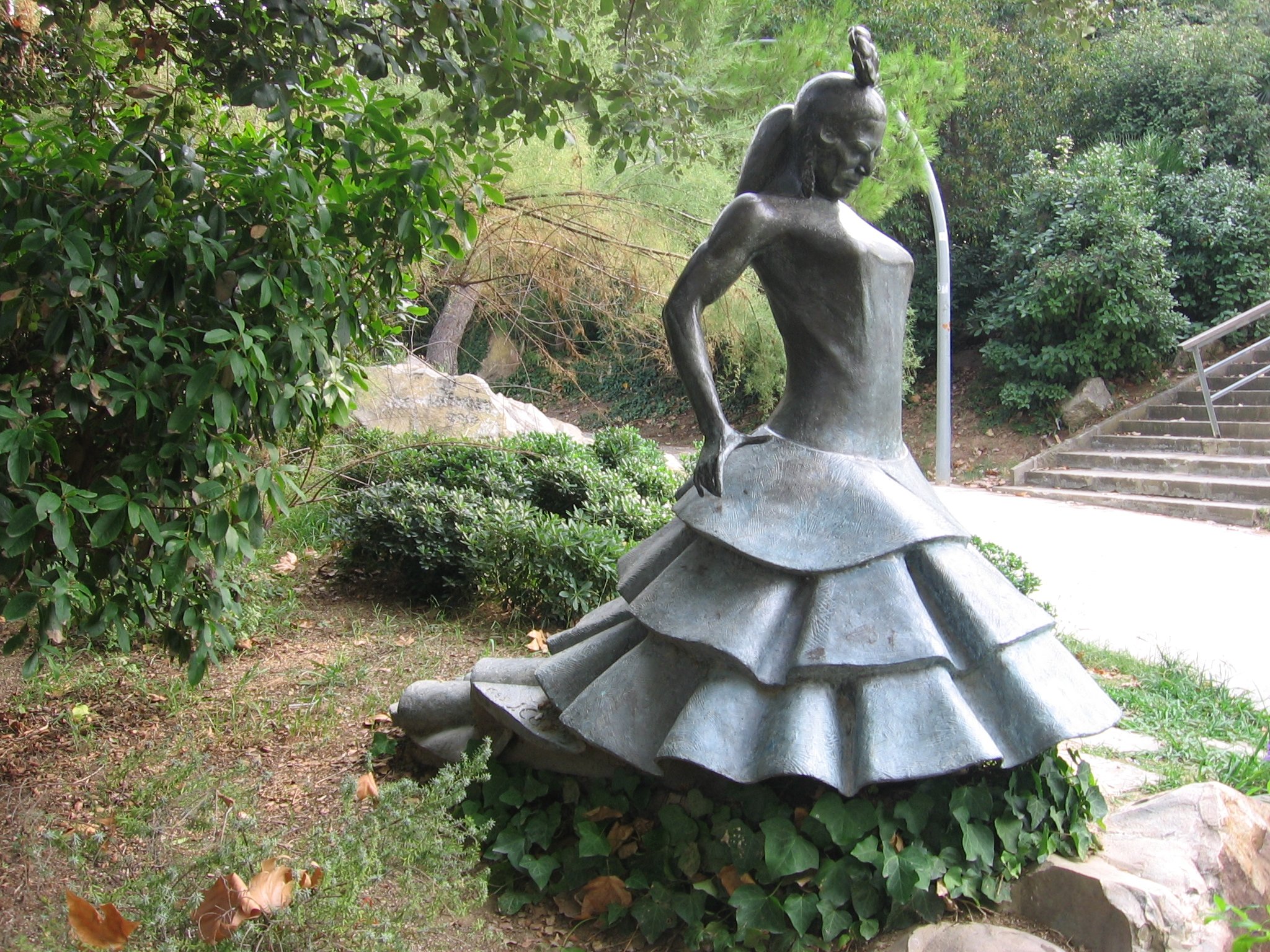 Bronze memorial sculpture of Carmen Amaya in a ruffled dress in Barcelona's Joan Brossa gardens.