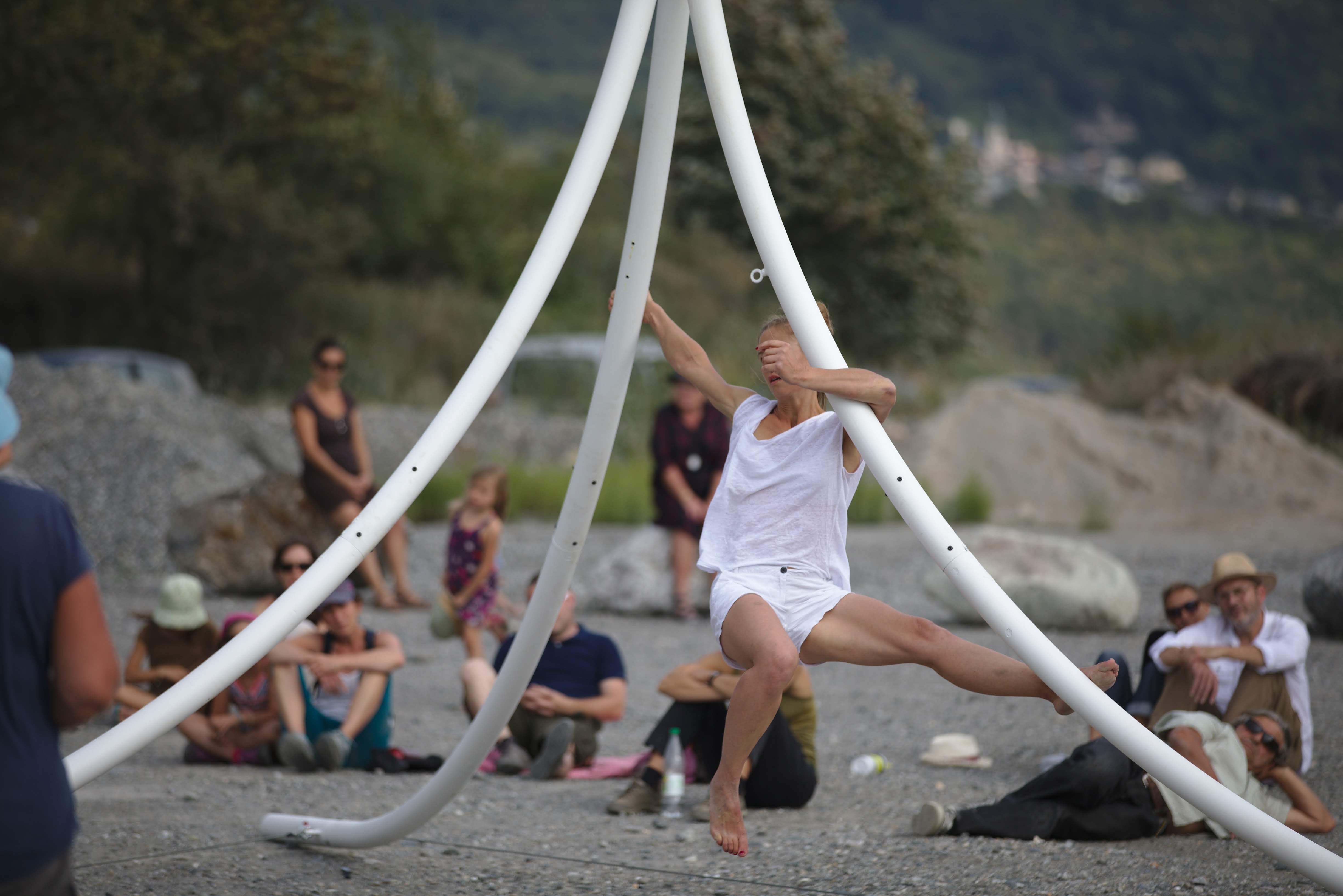 Chloé Moglia extending along a curved metal structure during a slow outdoor aerial performance