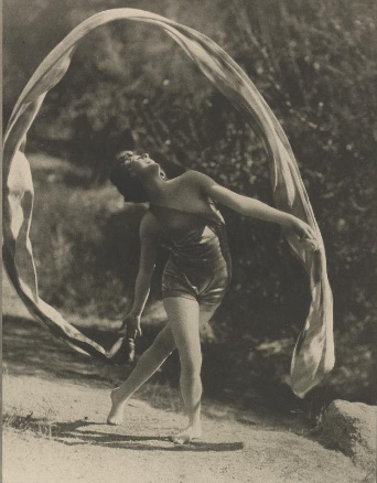 Doris Humphrey dances outdoors while a long translucent scarf arcs above and around her in 1921.