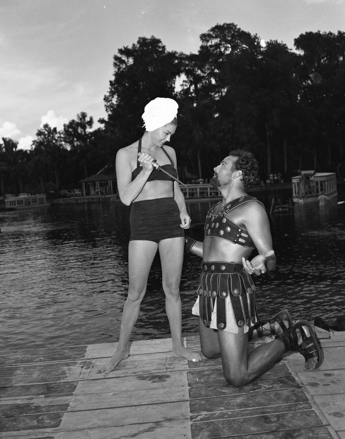 Esther Williams and Howard Keel kneeling beside a Florida swimming pool during a film production