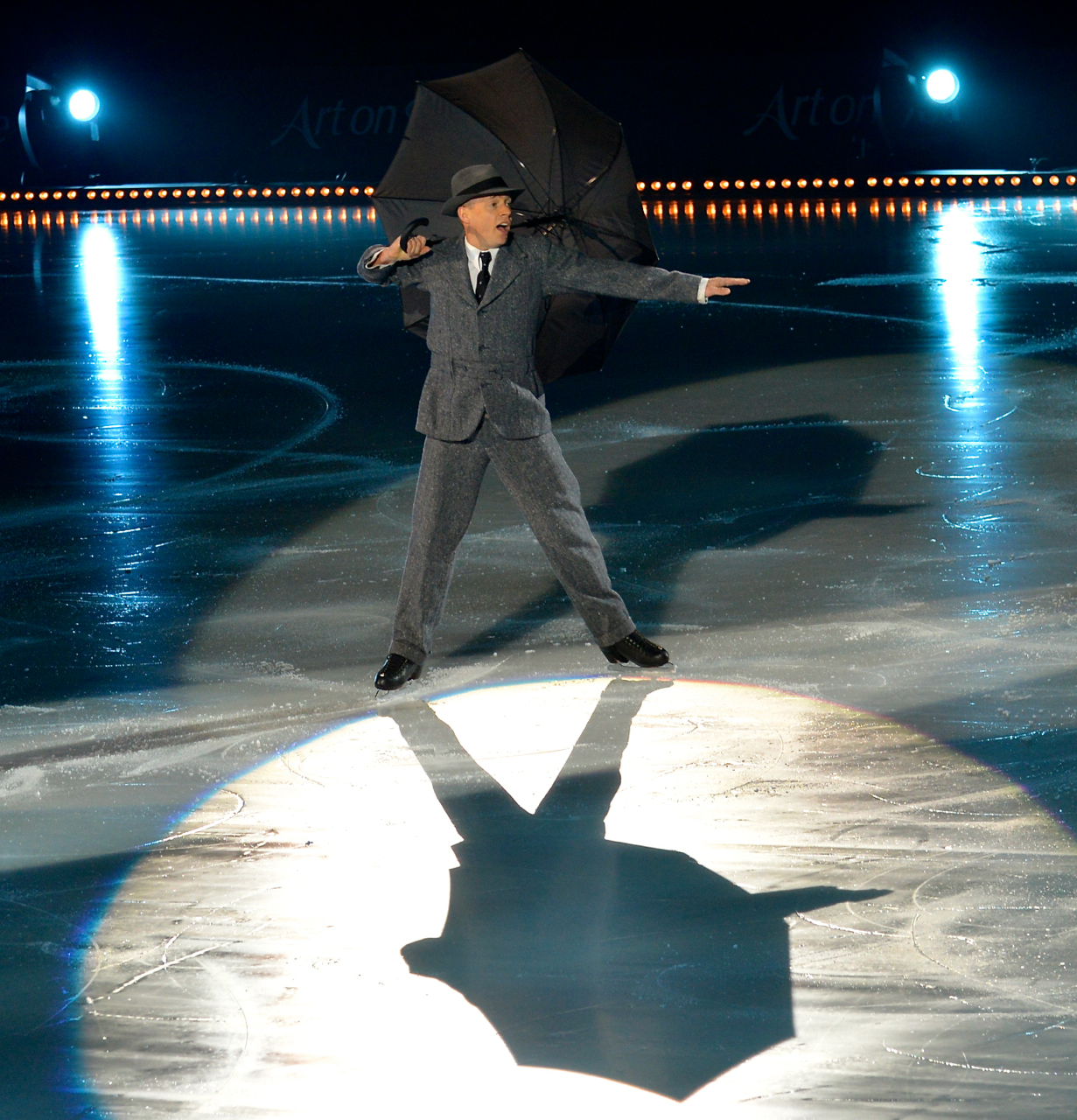 Kurt Browning holding an open umbrella under a spotlight during Art on Ice in 2014