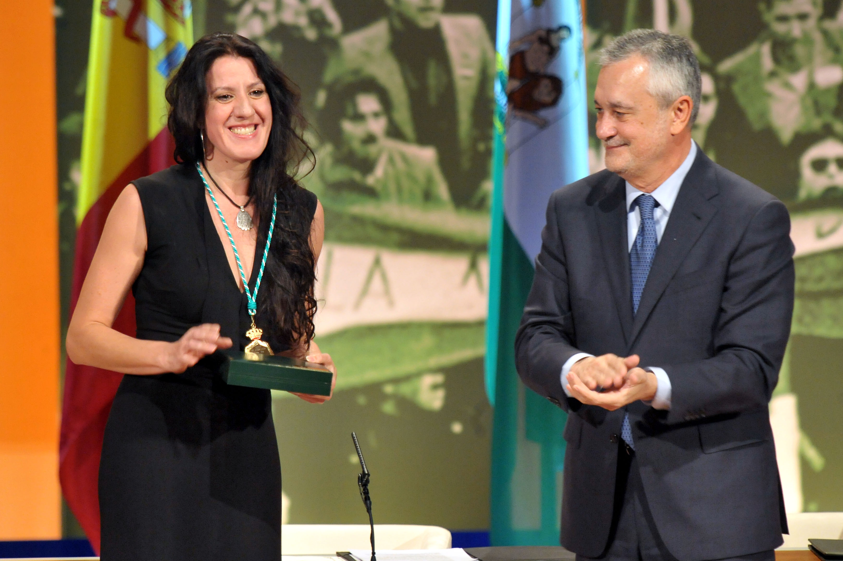 María Pagés smiling while holding the Medal of Andalusia beside regional president José Antonio Griñán in 2011.