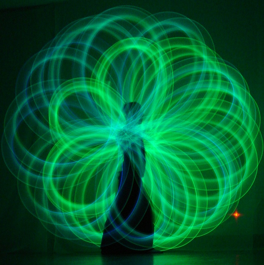 Long-exposure green light circles made by poi artist Nick Woolsey against a black background