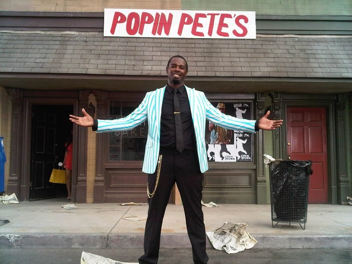 Popin’ Pete standing with his arms open beneath the Popin Pete’s storefront sign during filming of Chris Brown’s Yeah 3x video in 2010.