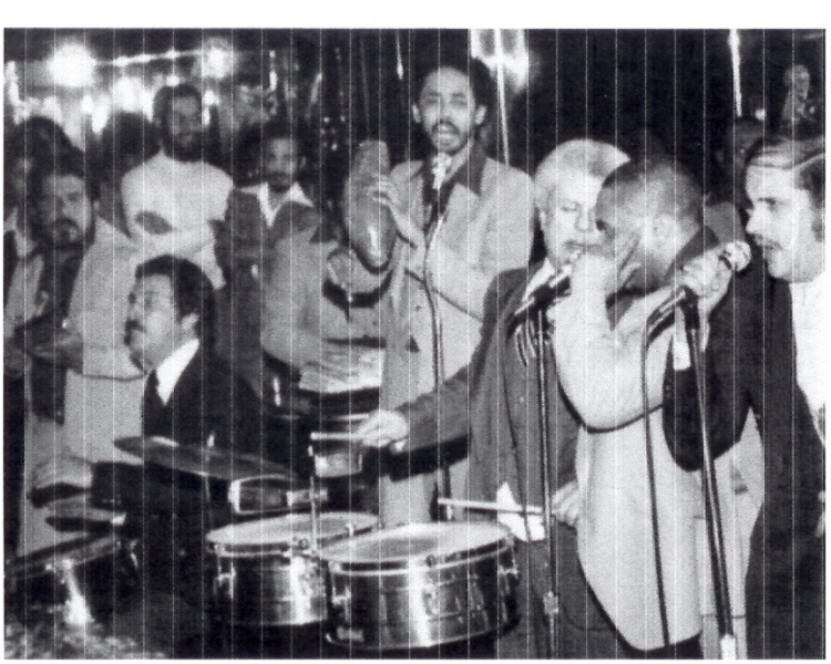 Tito Puente playing timbales beside radio host Roger Dawson at the Corso