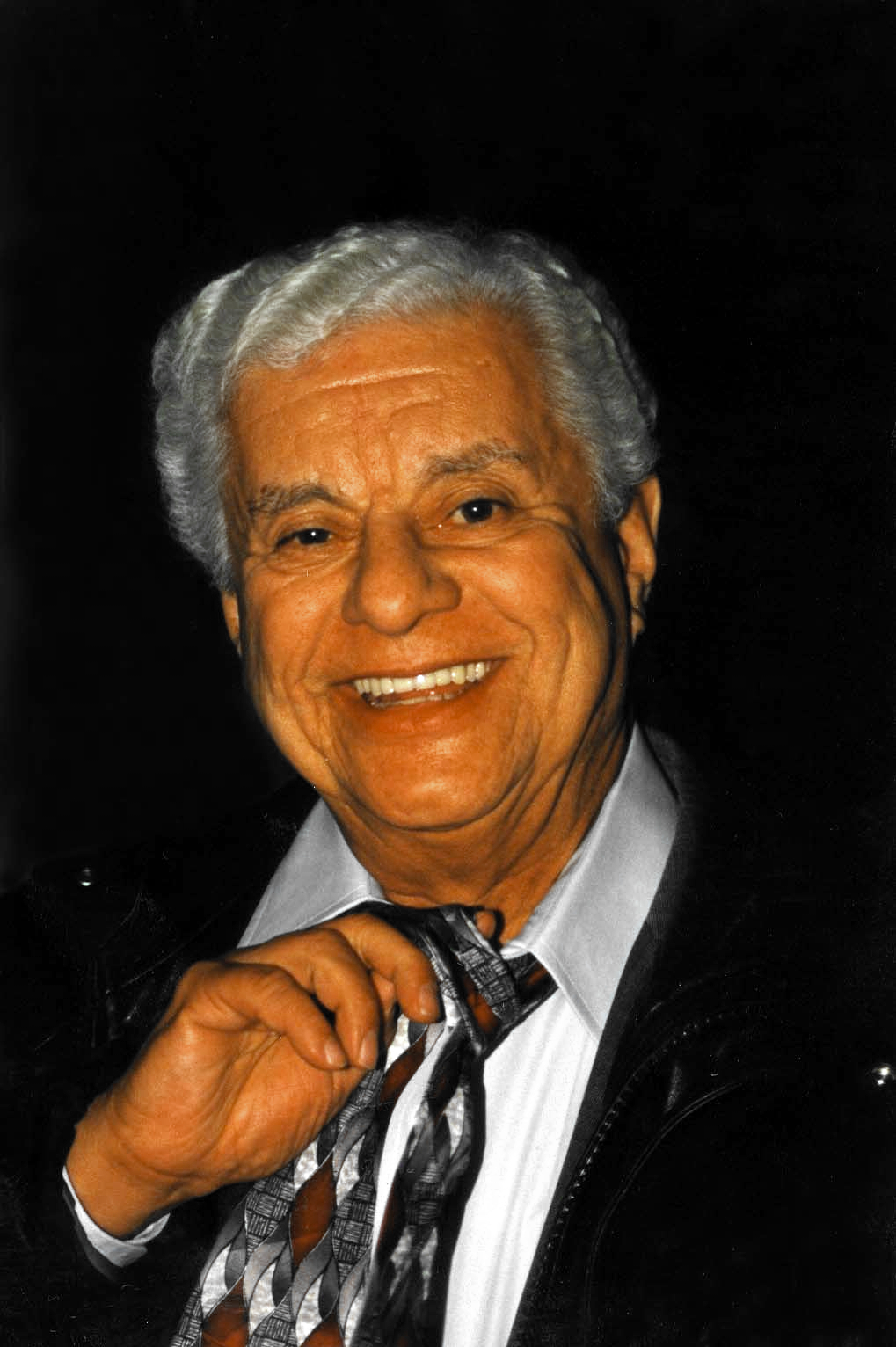 Formal portrait of Tito Puente smiling in a dark suit