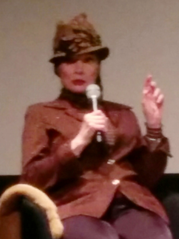 Toni Basil speaking into a microphone at SFMOMA in 2016